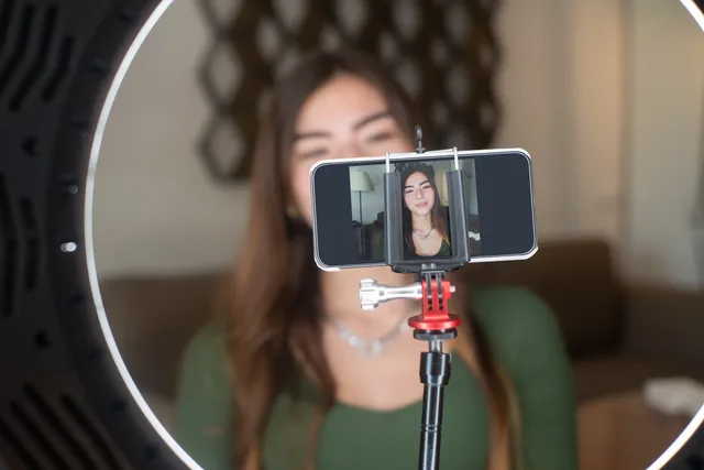 A young woman live streams from home using a smartphone and ring light setup. Micro influencer marketing: UK ASA and CMA disclosure rules
