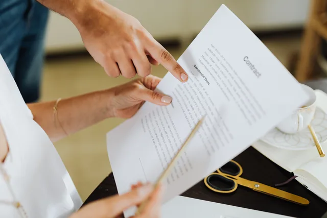 Close-up of two people discussing a business contract at a desk in an office setting. Choosing a micro influencer marketing supplier without the sales pitch
