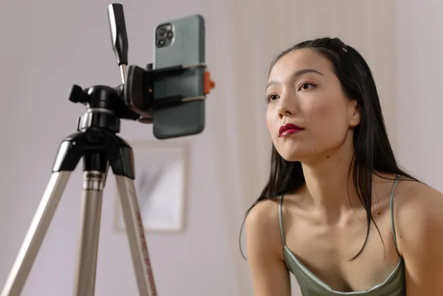 Asian woman recording a vlog indoors using a smartphone on a tripod. Micro influencer marketing UK regulations: label gifted posts, document a lawful basis for creator data and check IR35